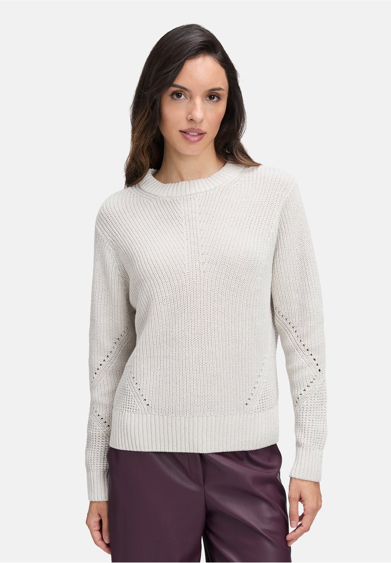 Hellgrauer gestrickter Pullover mit geripptem Kragen, dezentem strukturiertem Muster und seitlichen Belüftungsdetails, kombiniert mit dunkelvioletten Hosen.