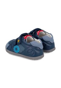 Zapatos de charol para niños pequeños en color azul marino, con detalles de ante, cintas de velcro, detalles estampados y suelas de goma grises. Diseño de puntera redondeada.