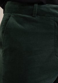 Tmavě zelené manšestrové kalhoty s měkkou strukturou, rovného střihu, s bočními kapsami a pasem pro přiléhavý vzhled.