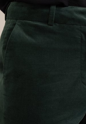 Sötétzöld kordbársony nadrág, puha tapintással, egyenes szabással, oldalsó zsebekkel és derékpánttal a fitted megjelenés érdekében.