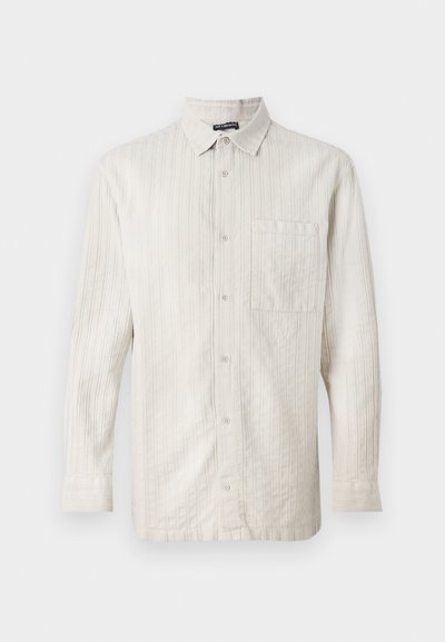 Cămașă bej deschis cu mânecă lungă, cu un model de dungi verticale, nasturi în față, un buzunar pe piept și o textură a țesăturii moale.