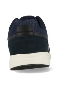 Navy blue sneaker featuring a mix of textured denim and smooth suede, with a contrasting black heel accent and a white rubber outsole.