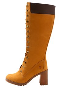 Bota hasta la rodilla hecha de cuero marrón claro con un acabado suave, que presenta una parte superior de marrón oscuro, diseño con cordones y un tacón cuadrado.
