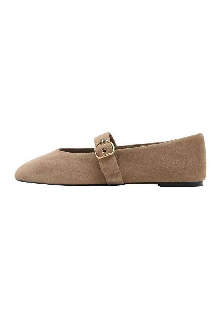 Beige mokkasiinimainen tasapohjainen kenkä, jossa on terävä kärki ja säädettävä hihna, jossa on metallinen solki sivulla kiinnitystä varten.