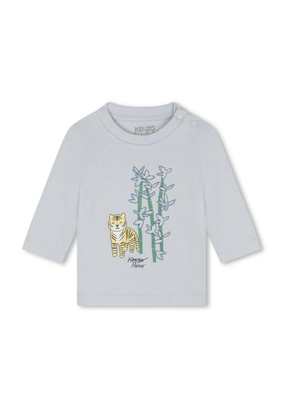 Chemise à manches longues bleu clair avec une illustration de tigre rayé jaune et noir à côté de bambous. Deux boutons pression sur l'épaule.