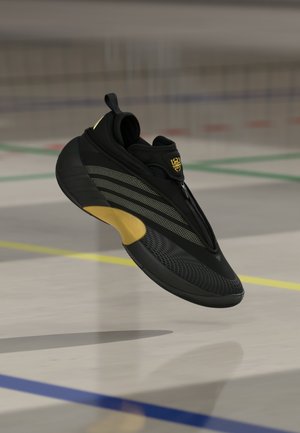 Sort atletiksko med et strømlinet design, der har lynlåslukning, strukturerede mønstre, gyldne accenter og en rundet sål.
