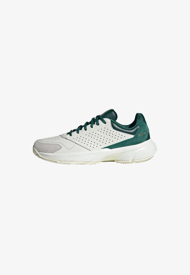 White athletic shoe with green accents, featuring a mix of smooth leather and suede, perforated design, and a textured rubber sole.