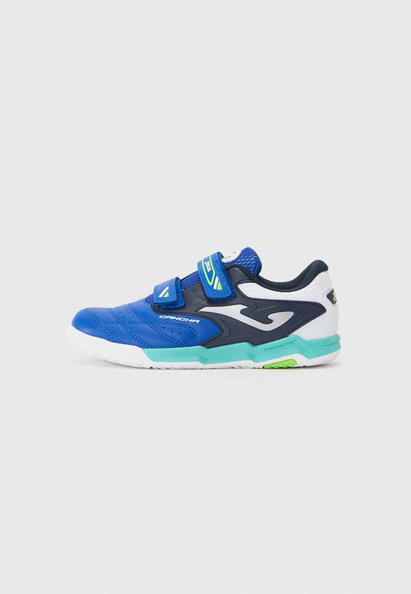 Zapatilla deportiva azul con una parte superior texturizada, doble cierre de Velcro, detalles en negro, suela blanca y un toque verde en el talón.