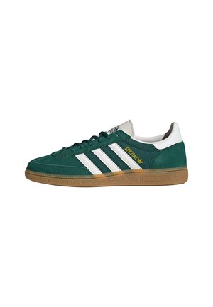 Groene suède Adidas Spezial sneaker met witte strepen, rubberen zool en witte hieltab, zijaanzicht op een witte achtergrond.