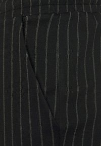 Czarna tkanina z pionowymi szarymi prążkami; gładka faktura; ma diagonalny szew dla dodatkowego detalu; odpowiednia do eleganckich strojów.