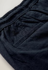 Tengerészkék szövet rövidnadrág elasztikus derékpánttal, texturált felülettel és oldalzsebekkel, melyeken pliszírozott részletek találhatók.