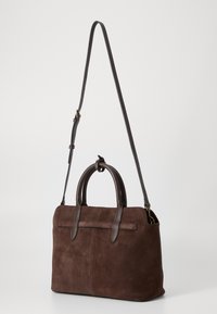 Braune Wildleder-Handtasche mit dunklen Lederakzenten, doppelten oberen Griffen und einem abnehmbaren Schultergurt. Rechteckige Form mit minimaler Verzierung.