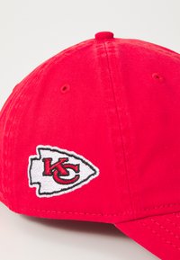 Cappellino da baseball rosso in cotone con visiera curva e logo ricamato dei Kansas City Chiefs in bianco e nero sul lato anteriore sinistro.
