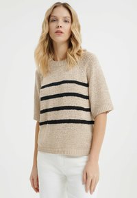 Beżowy sweter robiony na drutach z czarnymi poziomymi paskami, krótkimi rękawami, okrągłym dekoltem i prążkowanym wykończeniem. Teksturowana tkanina o luźnym kroju.
