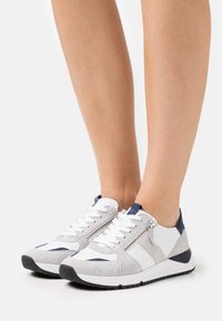 Atletiska sneakers i vitt, grått mocka och marina accenter; har snörning fram och sidodragkedjedetalj. Tjock svart gummisula.