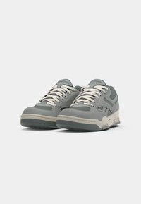 Par obu sivih Reebok tenisica s bijelim vezicama i bež potplatima prikazanih iz prednje lijeve strane na bijeloj pozadini.