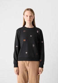 Felpa nera con vari patch ricamati, tra cui fiori e simboli. Polsini e orlo a costine, vestibilità rilassata, texture del tessuto morbida.
