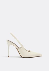 Chaussure à talon aiguilles à bride arrière de couleur crème, bout pointu et finition lisse sur un fond uni.