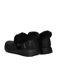 Zapatillas negras sin cordones con un suave puño de piel sintética, suela de goma plana y parte superior lisa. Presentan un botón decorativo en el costado.