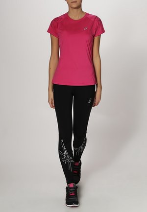 Rosa Sport-T-Shirt mit kurzen Ärmeln, kombiniert mit schwarzen Leggings, die weiße diagonale Linienmuster aufweisen, und schwarzen Sportschuhen.