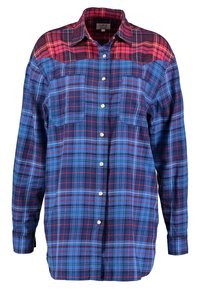 Camicia a quadri con motivi blu e rossi, chiusura a bottoni davanti, due tasche sul petto, maniche lunghe e colletto classico.