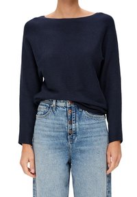 Jersey de punto acanalado marino con un amplio escote barco, combinado con jeans de mezclilla de talle alto en un azul claro con un cierre de botones y detalles desgastados.
