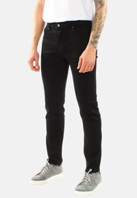 Jeans skinny neri in denim, con un design a cinque tasche standard, chiusura con bottone e zip, e una superficie liscia.