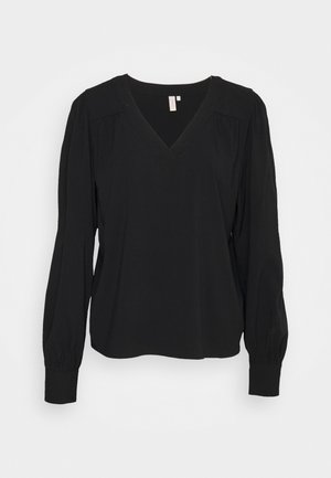 Svart långärmad blus med V-ringning, sammanknutna axelsömmar och elastiska ärmslut. Tillverkad av ett mjukt, lätt tyg.