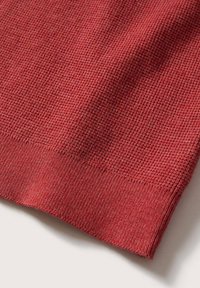 Tessuto rosso testurizzato con un motivo a nido d'ape, caratterizzato da un bordo in maglia liscia lungo il fondo, realizzato in un materiale morbido e leggero.