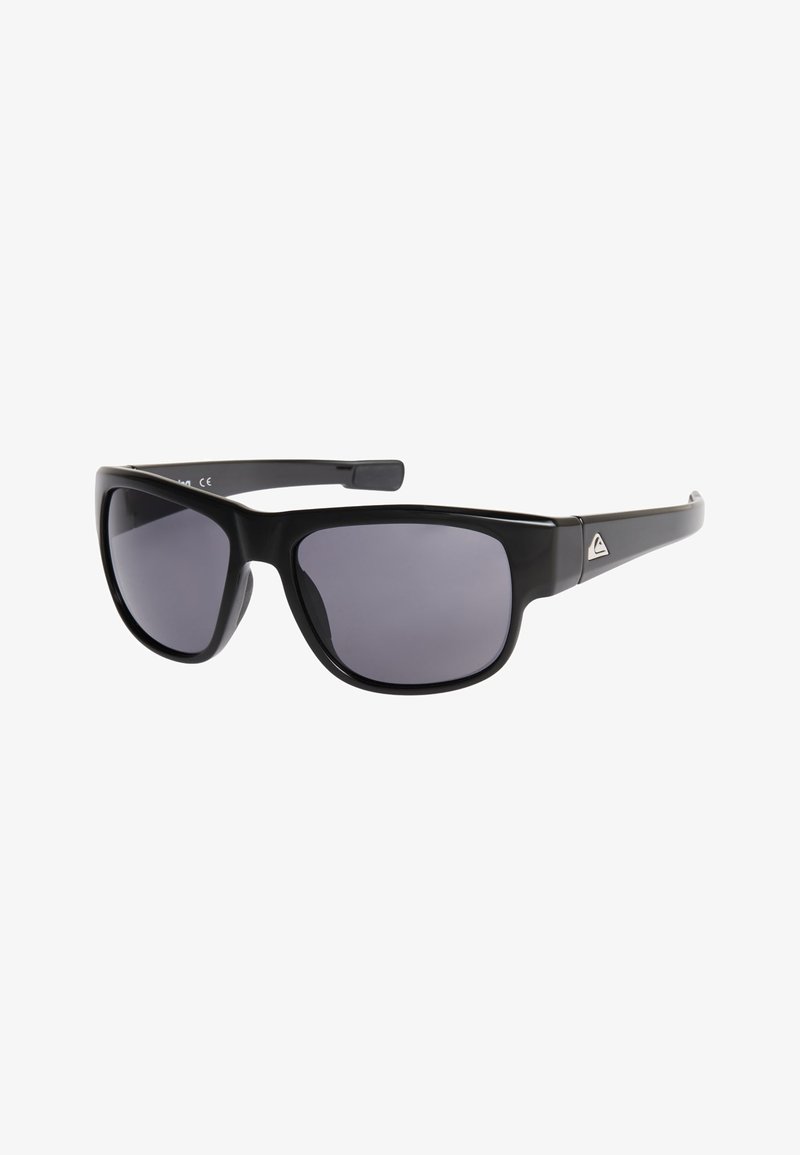 Lunettes de soleil rectangulaires noires avec des verres teintés foncés et un petit logo triangulaire argenté sur la branche, présentées sur un fond blanc.