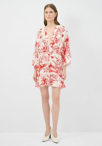 Bloemenprint jurk met rode patronen op een crèmekleurige achtergrond, wikkelstijl met een diepe halslijn, vloeiende mouwen en een gerimpelde zoom.