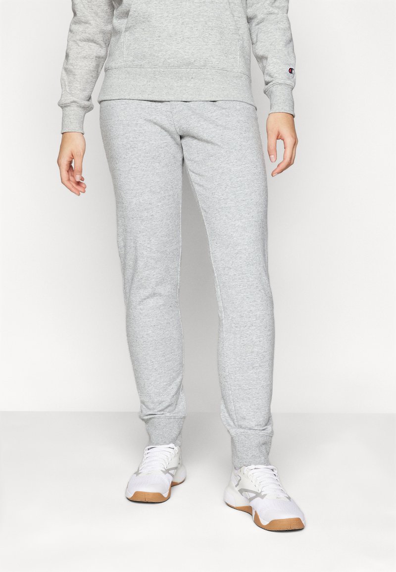 Graue Baumwoll-Jogginghosen mit einer schmalen Passform, elastischen Bündchen und einer glatten Textur. Kombiniert mit weißen Sneakers mit hellgrauen Akzenten.