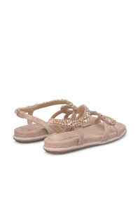 Sandali bassi beige con più sottili cinturini, decorati con scintillanti strass e una suola testurizzata. Materiale in morbida suede, design minimale.