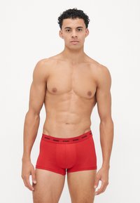 Boxer-briefs en coton rouge avec une coupe confortable, dotés d'une ceinture noir avec logo et d'une texture lisse.
