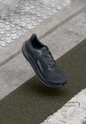 Black athletic shoe with a breathable mesh upper, textured design, and a cushioned sole. Features woven laces and side accents.