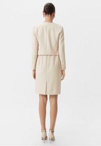 Beige skräddarsydd klänning med långärmade, en skräddarsydd överdel och en rak kjol, med en slits bak och enkel design.