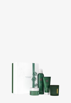 Green skincare gift set includes a jar, tube, and bottle; all feature curved shapes. Packaging is white with floral design and green accents.