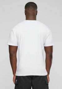 Hvid bomulds T-shirt med korte ærmer og rund halsudskæring. Glat tekstur. Bagfra vises der ingen yderligere grafikker eller mønstre.