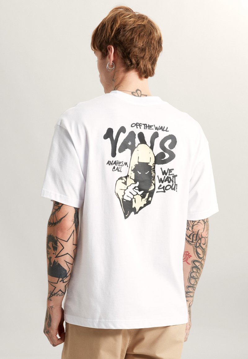 Camiseta blanca de algodón con un diseño gráfico en la parte posterior que incluye el texto "VANS", una ilustración de una mano y la frase "¡TE QUEREMOS!" en negro.