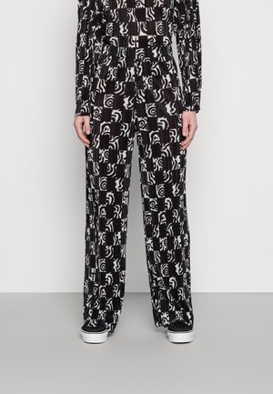 Calças largas de padrão preto e branco com textura plissada, apresentando desenhos abstractos e uma cinta elástica confortável.