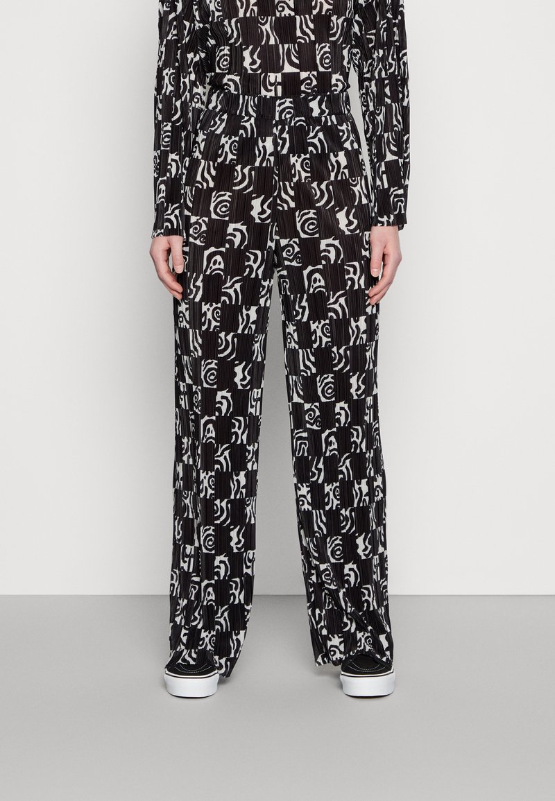 Calças largas de padrão preto e branco com textura plissada, apresentando desenhos abstractos e uma cinta elástica confortável.