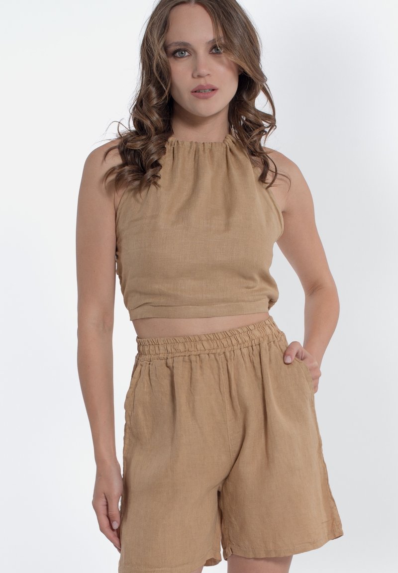 Completo due pezzi in lino color sabbia composto da un top corto con collo halter e pantaloni corti con vita elasticizzata e tasche laterali, realizzato in un morbido tessuto testurizzato.