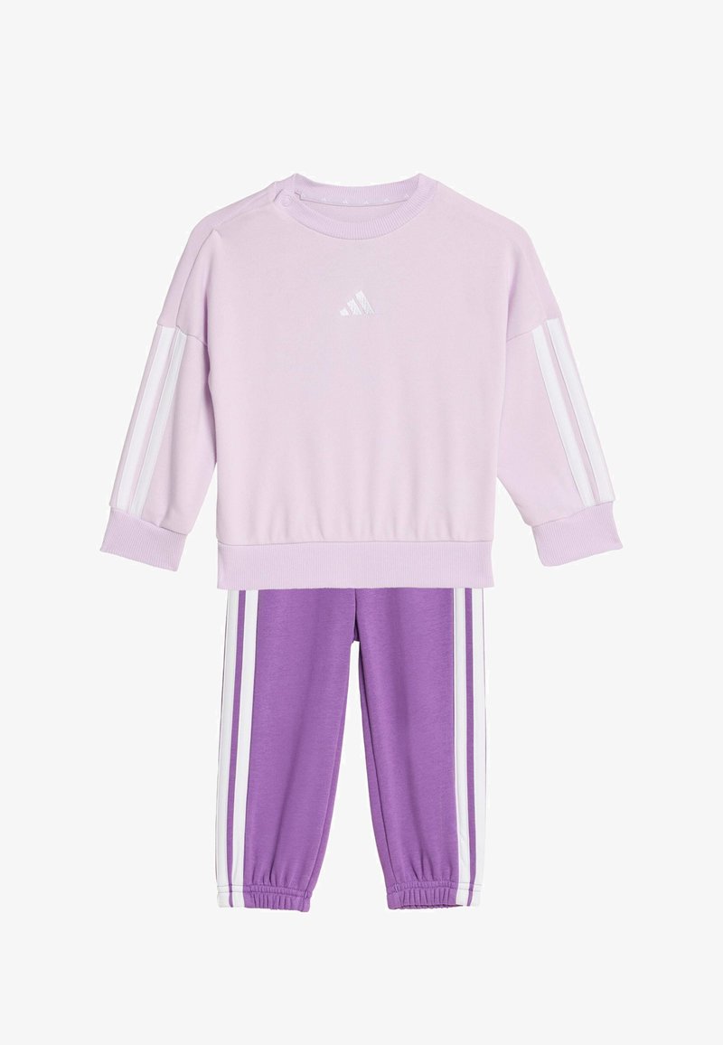 Sweat-shirt lilas avec des rayures blanches sur les manches, doté d'un col rond et d'une fermeture à pressions. Pantalon assorti violet avec des rayures blanches sur les côtés.