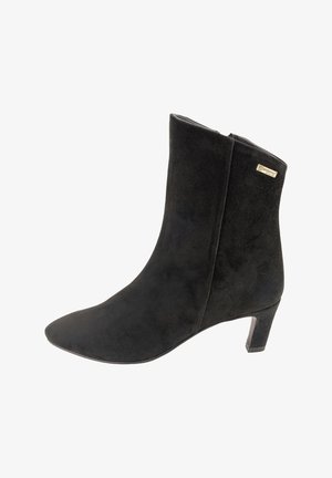 Botín de ante negro hasta el tobillo con punta afilada y un tacón bajo y apilado, que presenta un discreto logotipo metálico de la marca en el lateral.