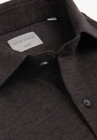 Slim fit -tyylinen, nappikiinnitteinen paita tummanruskeasta teksturoidusta kankaasta, jossa on klassinen kaulus, etiketti, jossa lukee "DAN JOHN", ja tummat napit.