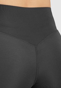 Leggings noirs taille haute en matériau extensible, dotés de coutures plates et d'une texture lisse, conçus pour le confort et la flexibilité.