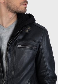 Černá kožená bunda se zipem vpředu a bočními kapsami, vybavená měkkou černou fleecovou kapucí a stříbrnými detaily.