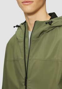 Olivgrüne wasserdichte Jacke mit Reißverschluss vorne, verstellbarem Kapuze und schwarzen Akzenten. Bietet eine glatte Textur und flache Nähte.