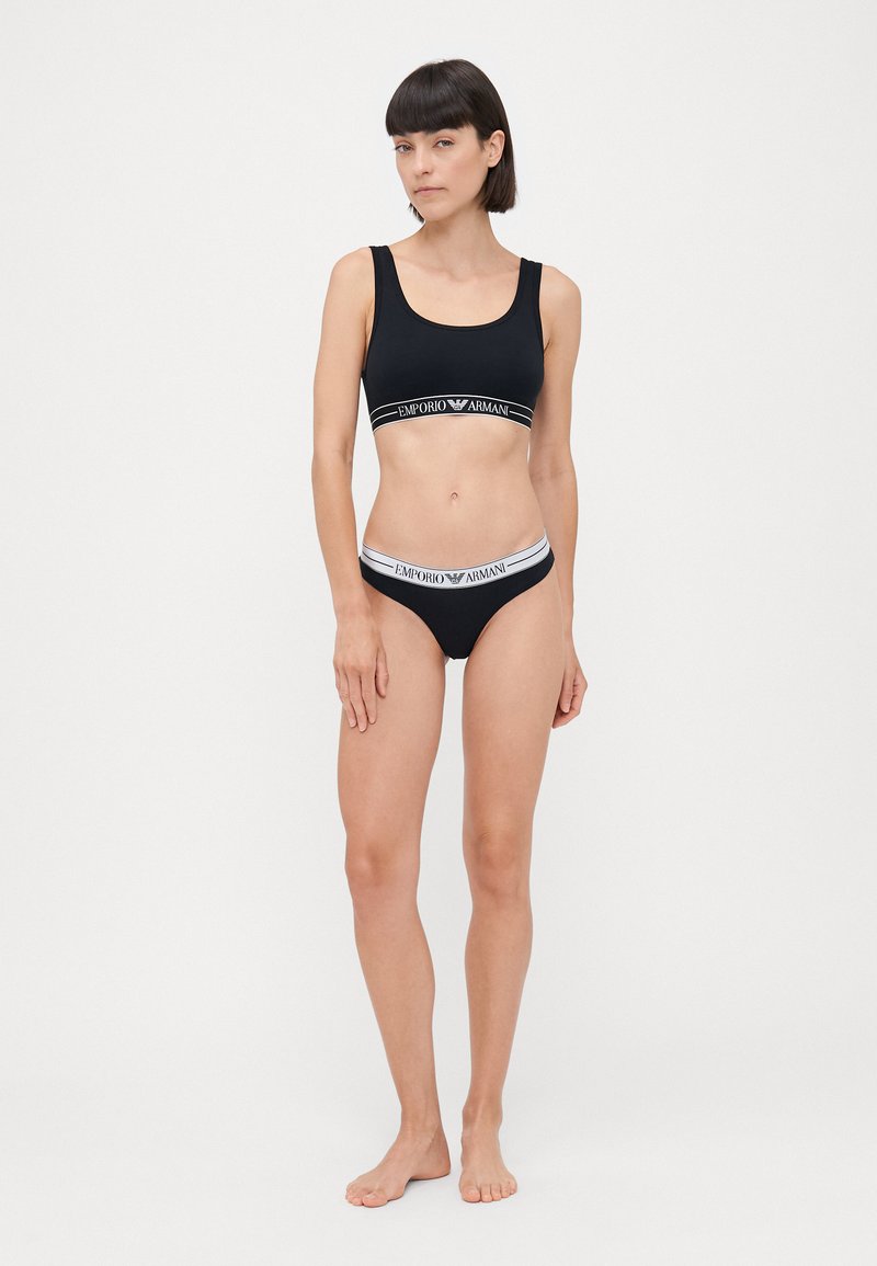 Black lingerie set featuring a sports bra and matching underwear. Both have contrasting elastic bands with the brand name in white text.