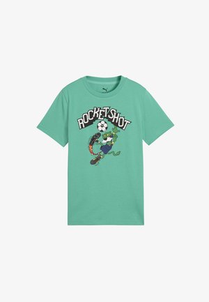 Maglietta verde con un alligatore cartone animato in blu che calcia un pallone da calcio a razzo fiammeggiante sotto il testo "ROCKET SHOT."